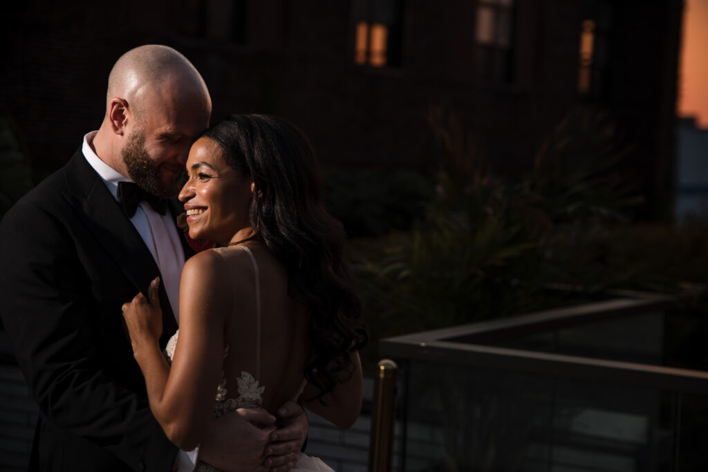 A couple embracing and smiling during a romantic moment at a 74 Wythe rooftop wedding.