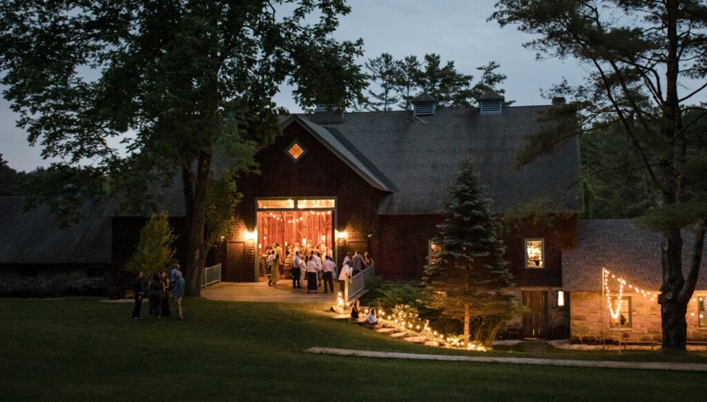 An evening gathering at Stonover Farm, a rustic venue with string lights and guests outside.