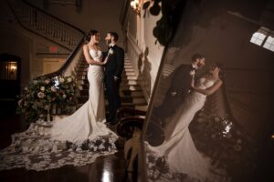 A bride and groom posing together on their Bourne Mansion wedding day, with their reflection visible on a polished surface.