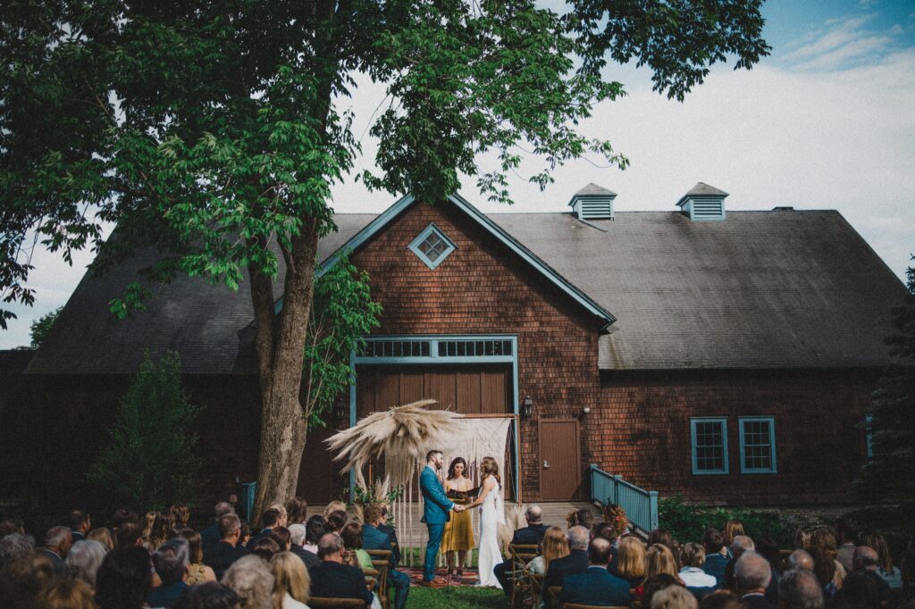 A couple exchanges vows at a Stonover Farm wedding ceremony in front of a rustic barn.