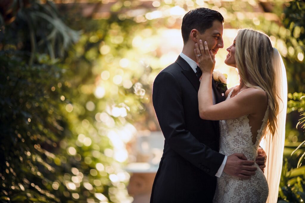A bride and groom share a tender moment in a sunlit greenhouse at Pleasantdale Chateau.