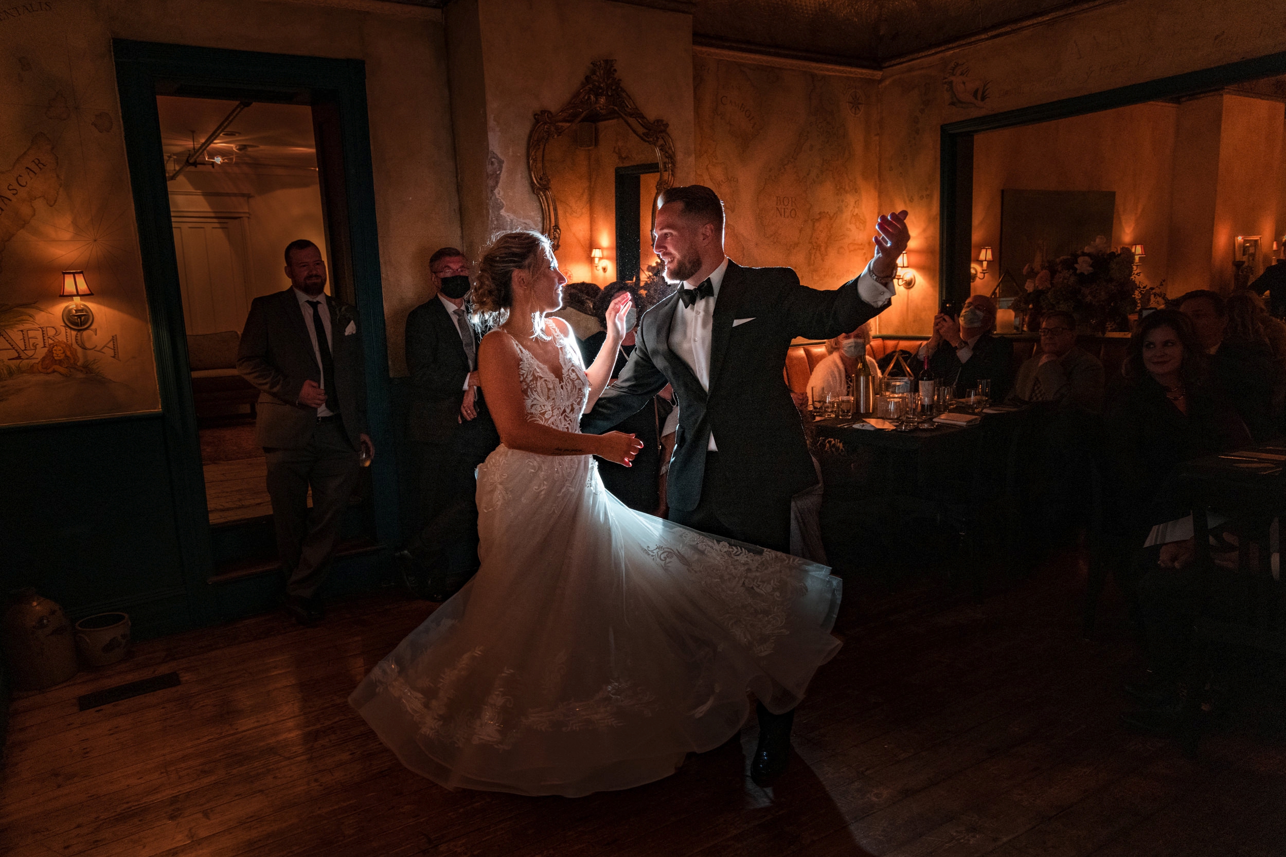 A bride and groom share their first dance at a Meadow Ridge on the Hudson Wedding, surrounded by guests in a dimly lit room.