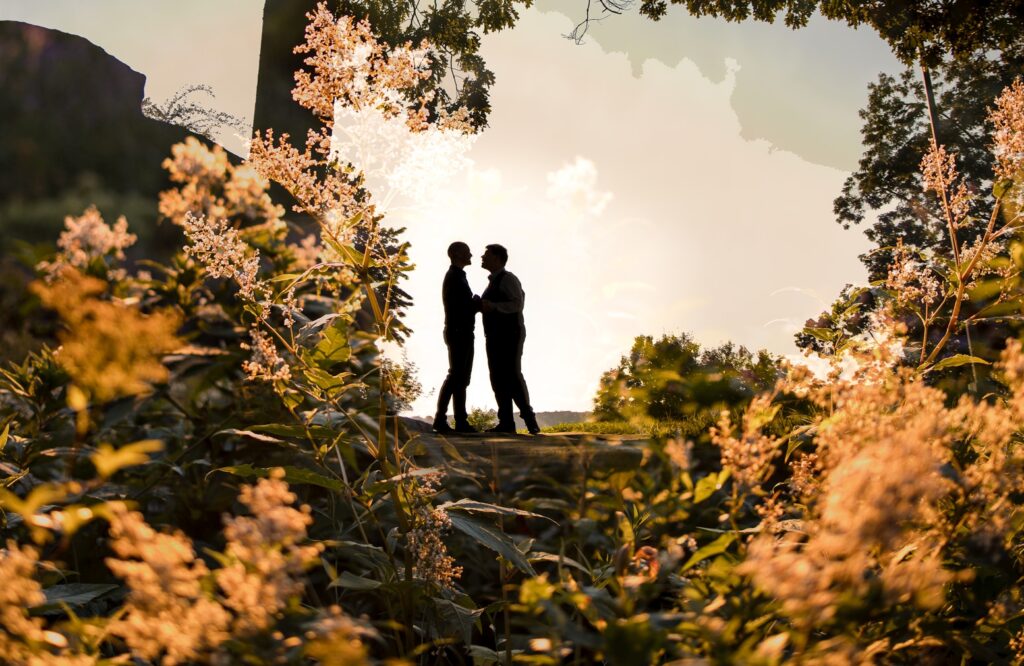 Two people standing under a tree at sunset in Fort Tryon Park, silhouetted against a warm, backlit natural setting for their engagement photos.