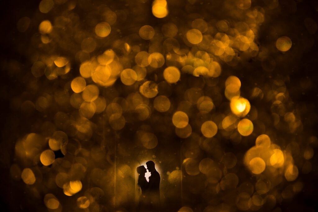 Silhouettes of a couple embracing at their Ritz Carlton Philadelphia wedding, surrounded by a golden bokeh light effect.