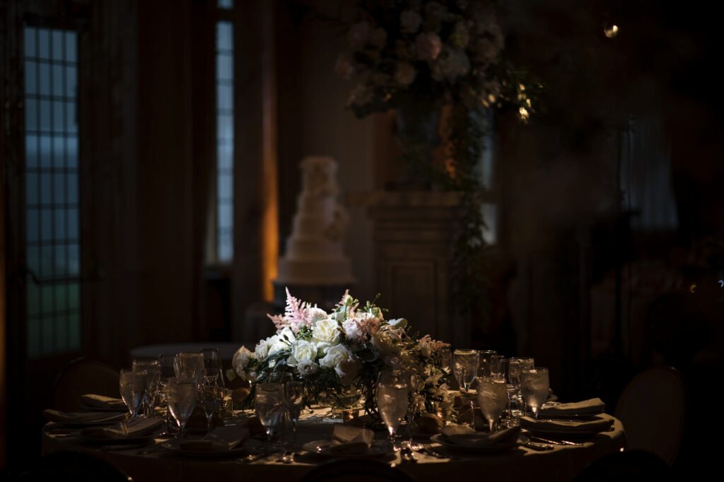 Elegant table setting with floral centerpiece in a dimly lit room for a Pleasantdale Chateau wedding.