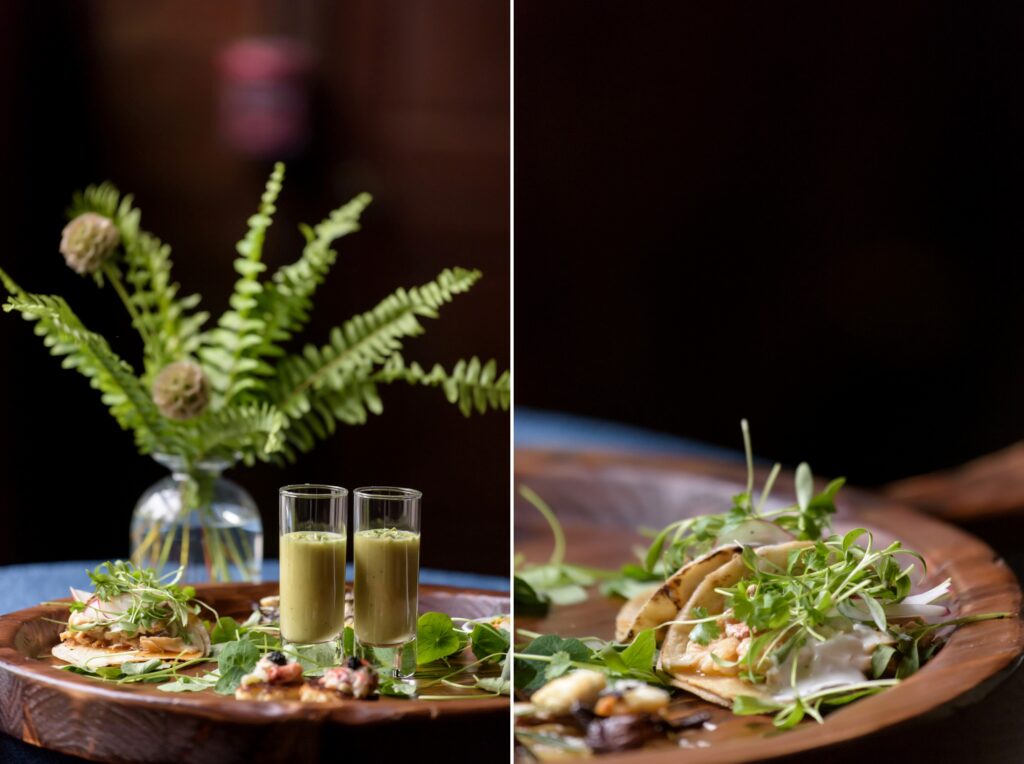 A gourmet appetizer served on a wooden plate accompanied by two shot glasses of soup, with a decorative vase of ferns and flowers in the background, perfectly designed for Hudson Valley Weddings at The Hill