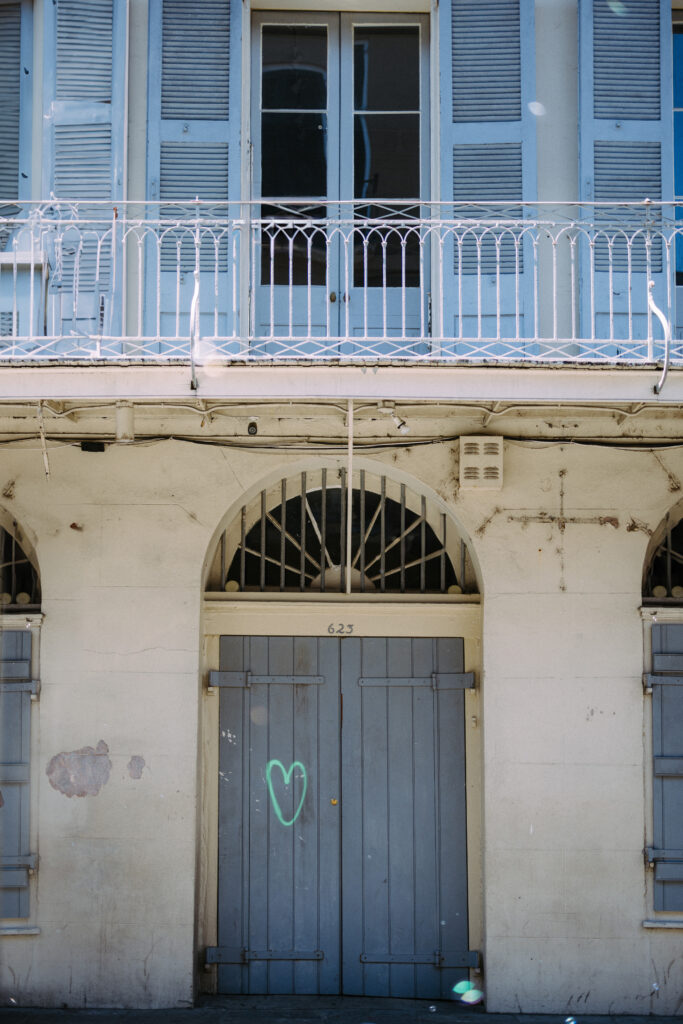 A blue and white building with a heart painted on the blue wooden doors in New Orleans after Mardi Gras