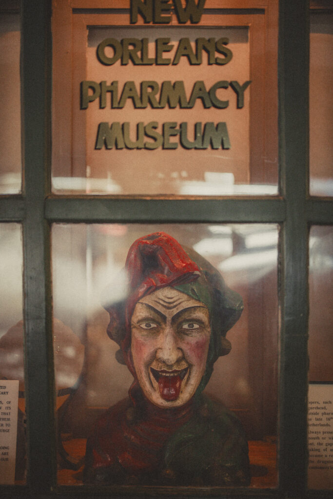 New Orleans Pharmacy Museum sign in a window with a clown head
