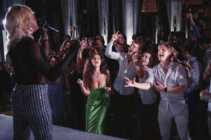 Wedding guests at a reception standing in front of a stage with a live band