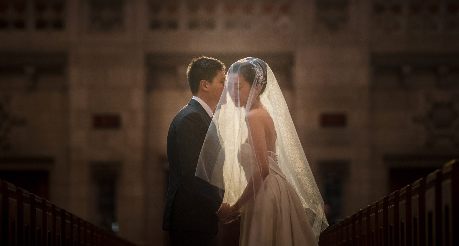 Bride and groom sharing a tender moment under soft lighting in the ornate hall of Princeton University.