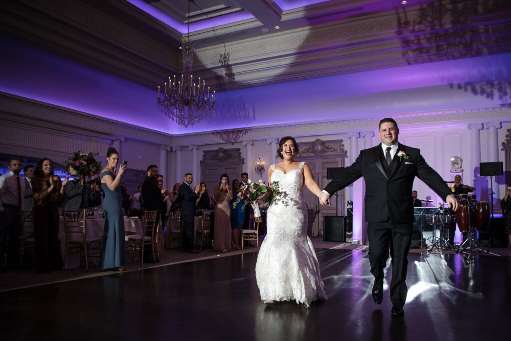 Bride and groom make a jubilant entrance to their Park Chateau wedding reception ballroom.