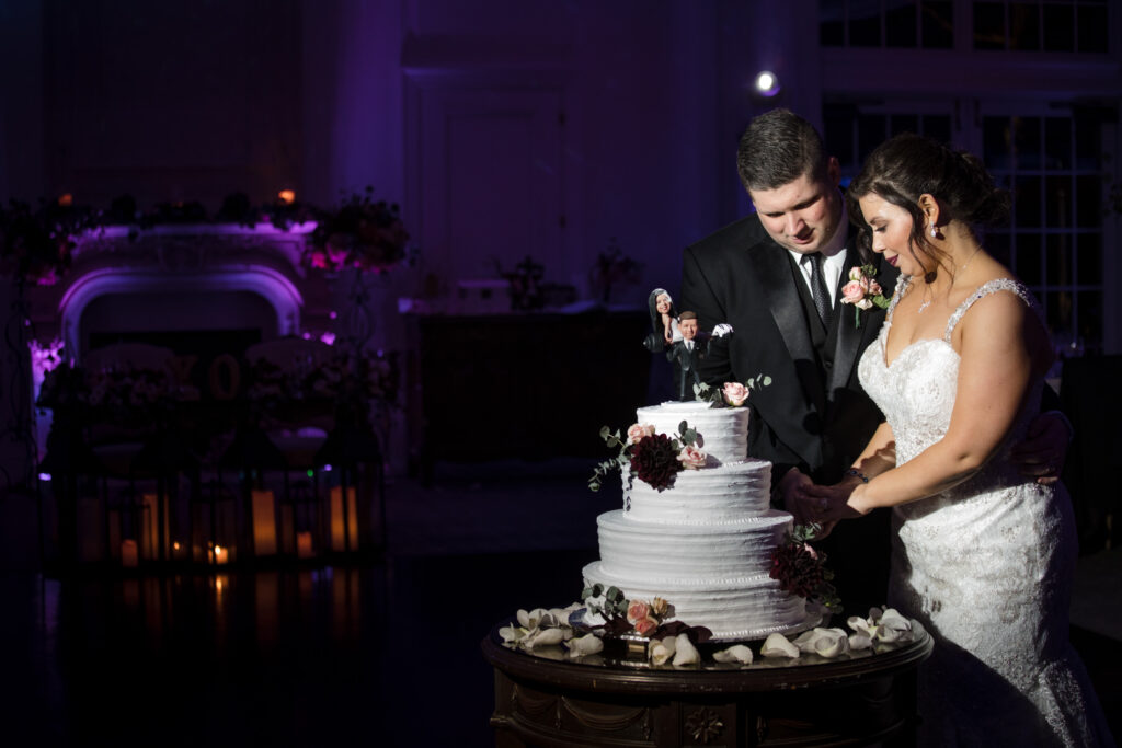 A bride and groom cutting their wedding cake together at their Park Chateau wedding in a dimly lit room.