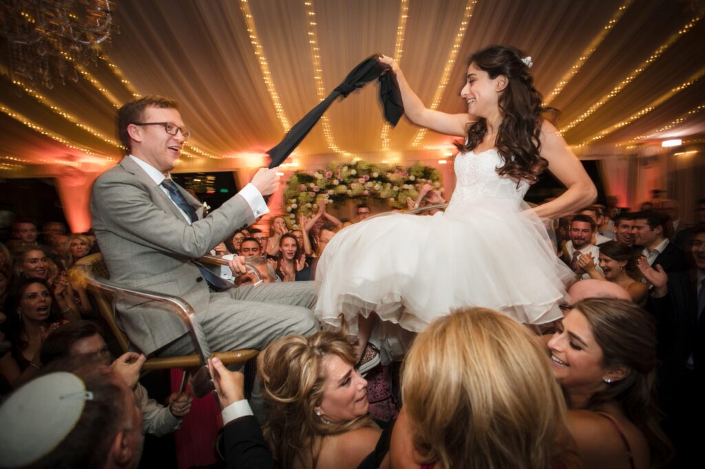 A bride and groom joyously dance at their Water Works Philadelphia wedding reception, surrounded by cheering guests.