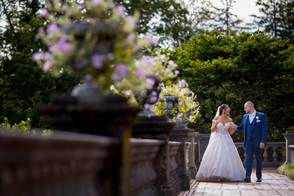 Bride and groom walking hand in hand in an Old Westbury Gardens setting.