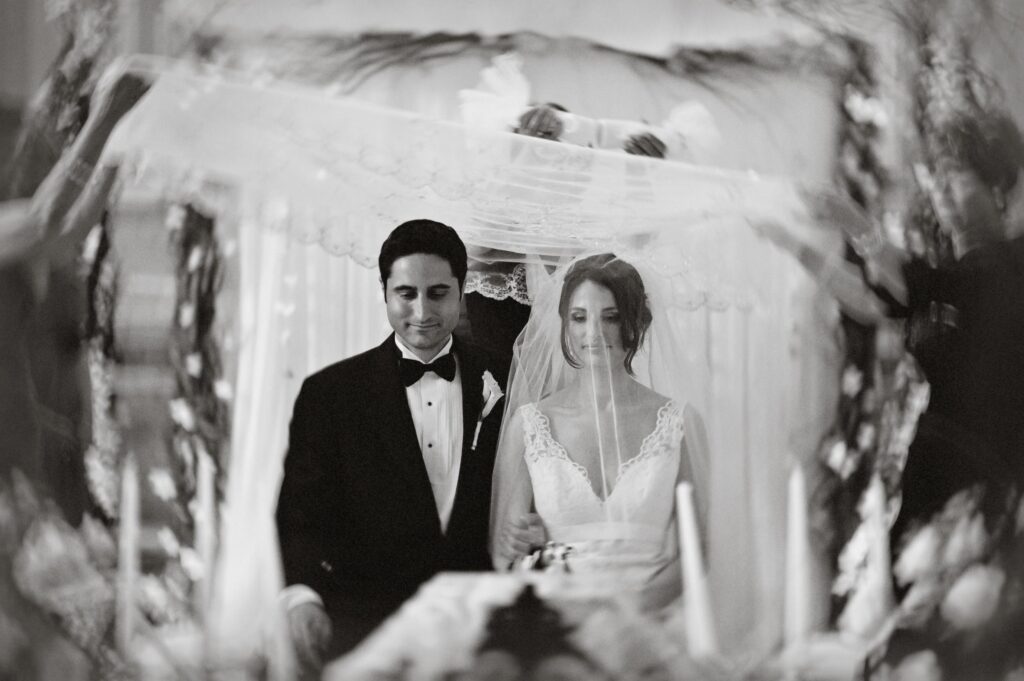 Bride and groom walking under a chuppah at their Please Touch Museum wedding, captured in a black and white photo.