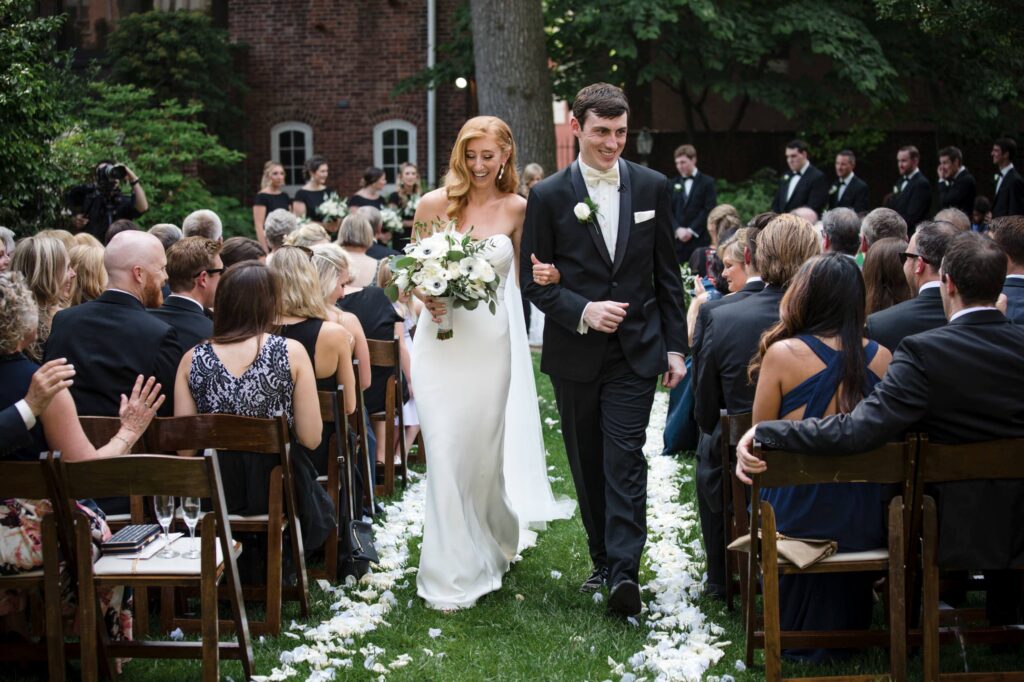 Bride and groom walking down the aisle at Powel House, smiling, as guests applaud during an outdoor Philadelphia wedding ceremony.