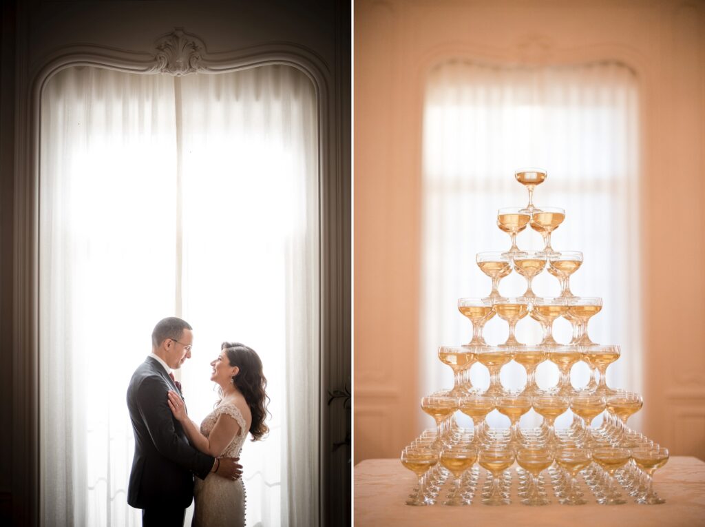 A couple embracing by a window with soft light and a champagne tower on a table to the right during their Pine Hollow Country Club wedding.