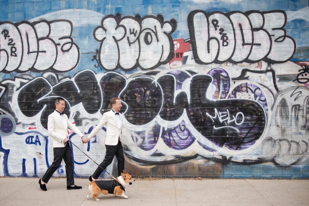 Two grooms and their dog walk around Williamsburg for wedding day portraits with graffiti and murals