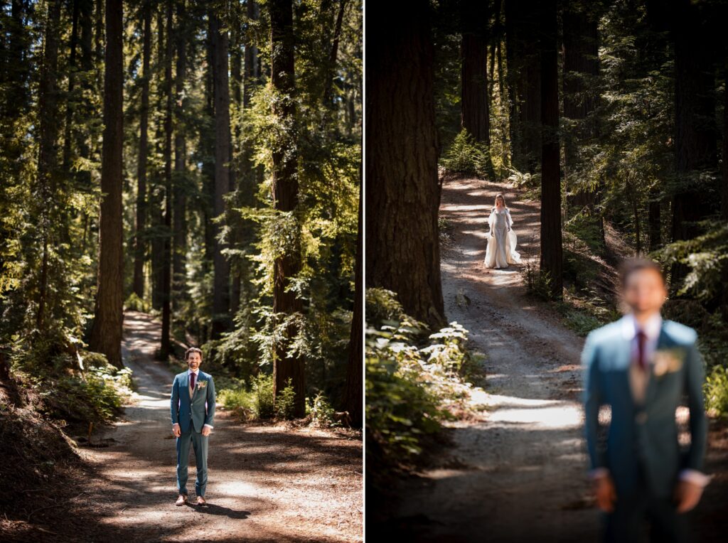 A groom in a blue suit stands on a forest path at their Nestldown wedding, while in the distance, a bride in a white dress walks towards him.