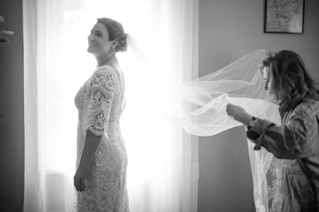 Smiling bride has veil held whilst getting ready