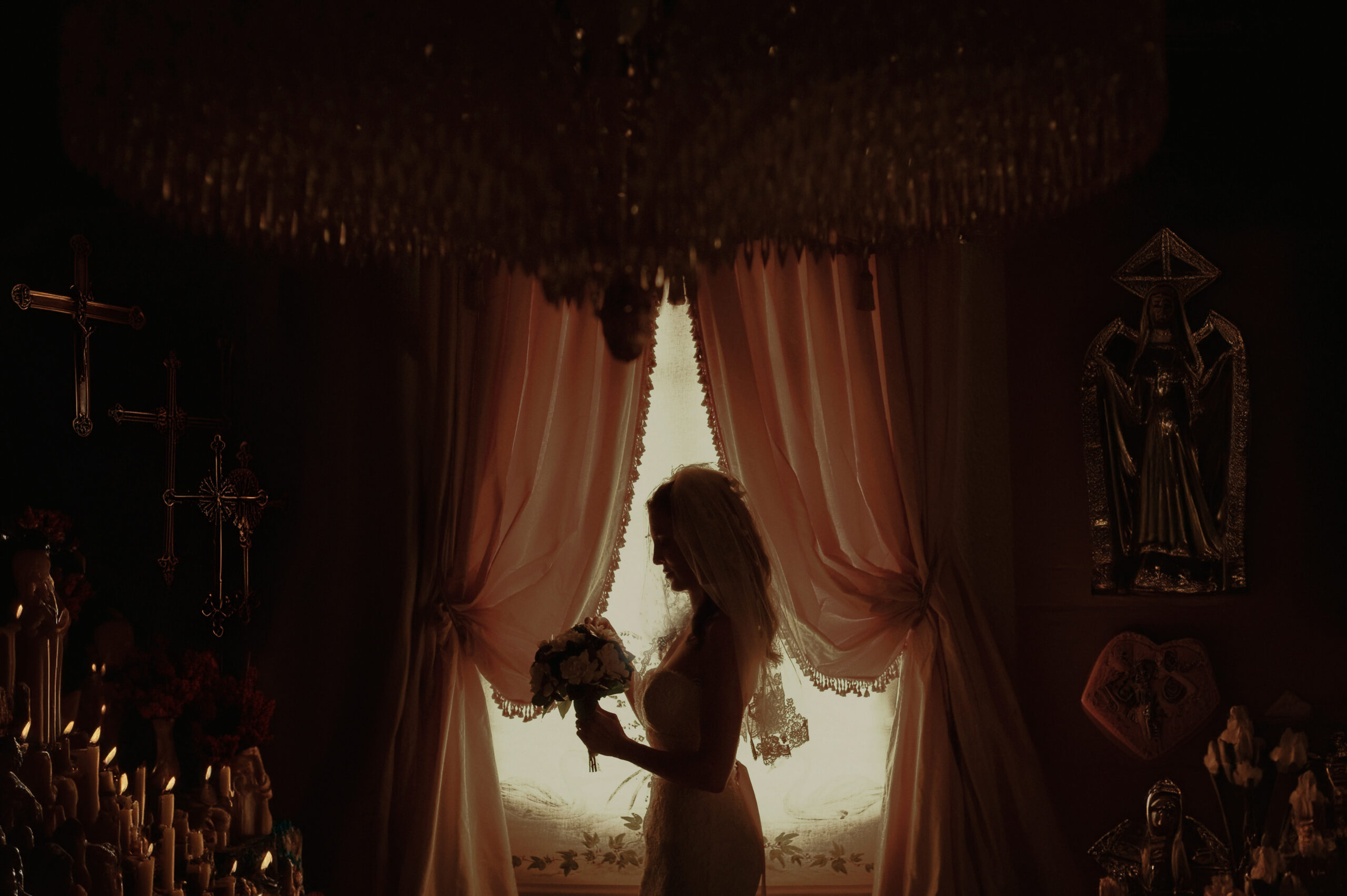A bride stands in a dimly lit room in an example of high-end wedding photography.