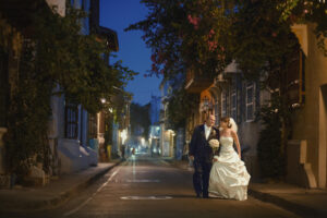 A couple walks with one another at night in the city streets.