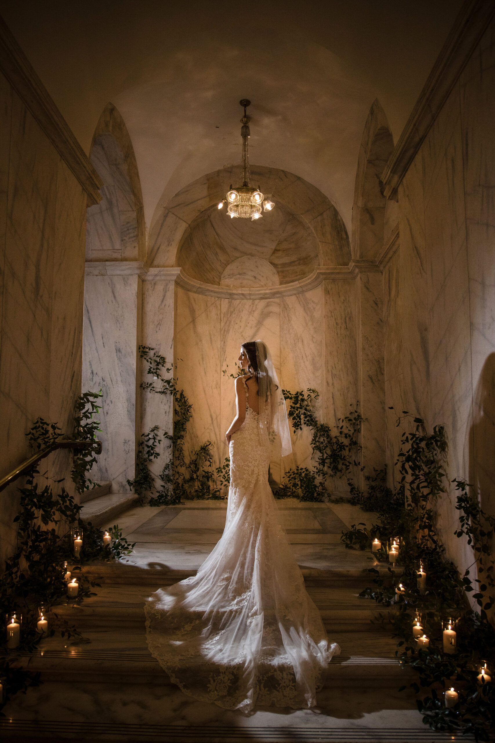 A bride walks up the steps inside a dimly lit room at her luxury wedding.