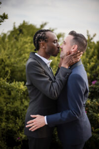 A couple leans in for a kiss on their wedding day outdoors.