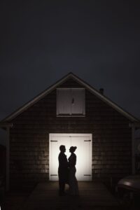 A silhouetted couple stands in front a barn at wedding venues in Mystic CT.