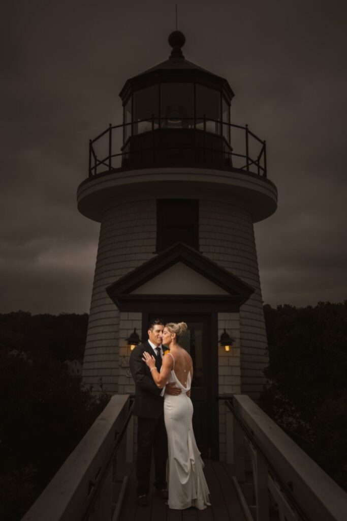 A couple shares a romantic moment in front of a white lighthouse Mystic CT's dreamy wedding venues.