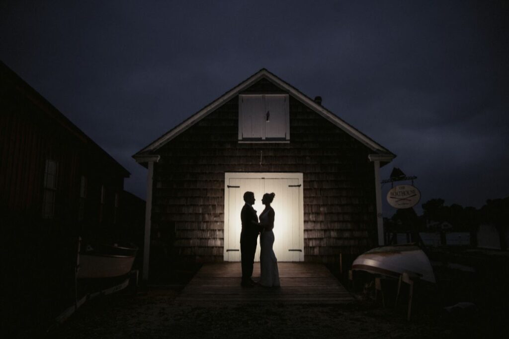 A couple facing each other in front of a dimly lit barn at Mystic CT Wedding Venues