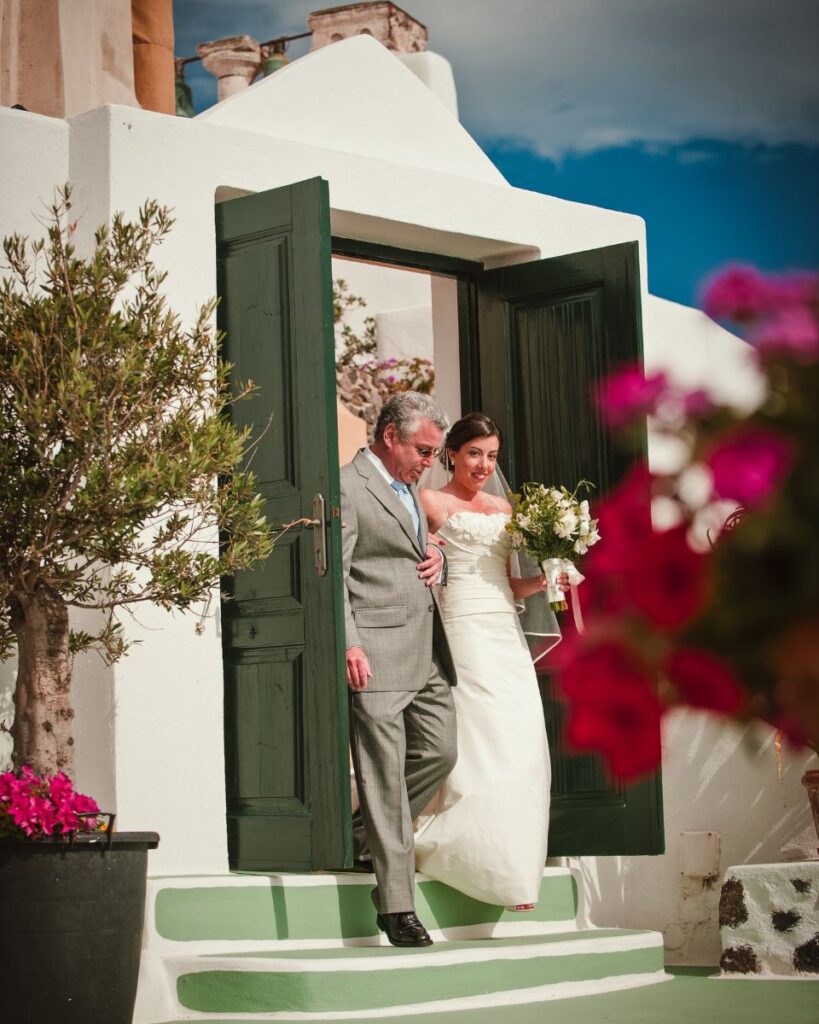 A bride and her father walking to one of the destination weddings in Santorini 