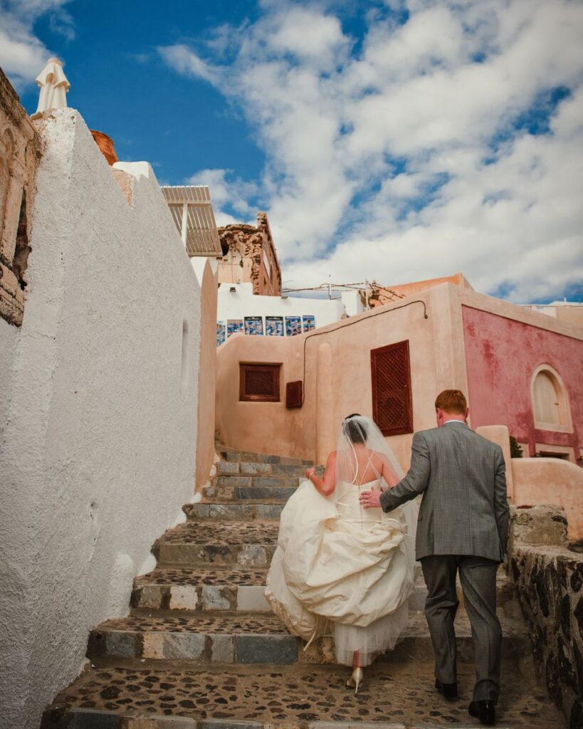 A couple walking up the stairs and having one of the destination weddings in Santorini 