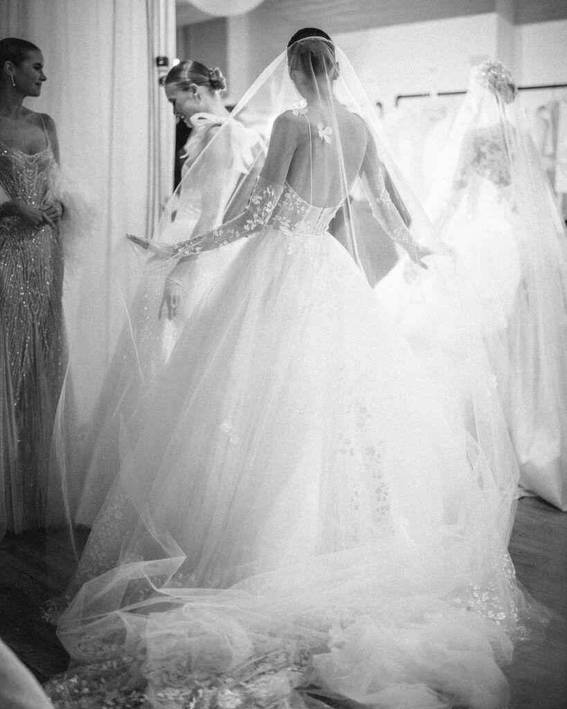 Brides in elegant white gowns and veils from the Pnina Tornai AURA Collection gather in a fitting room.