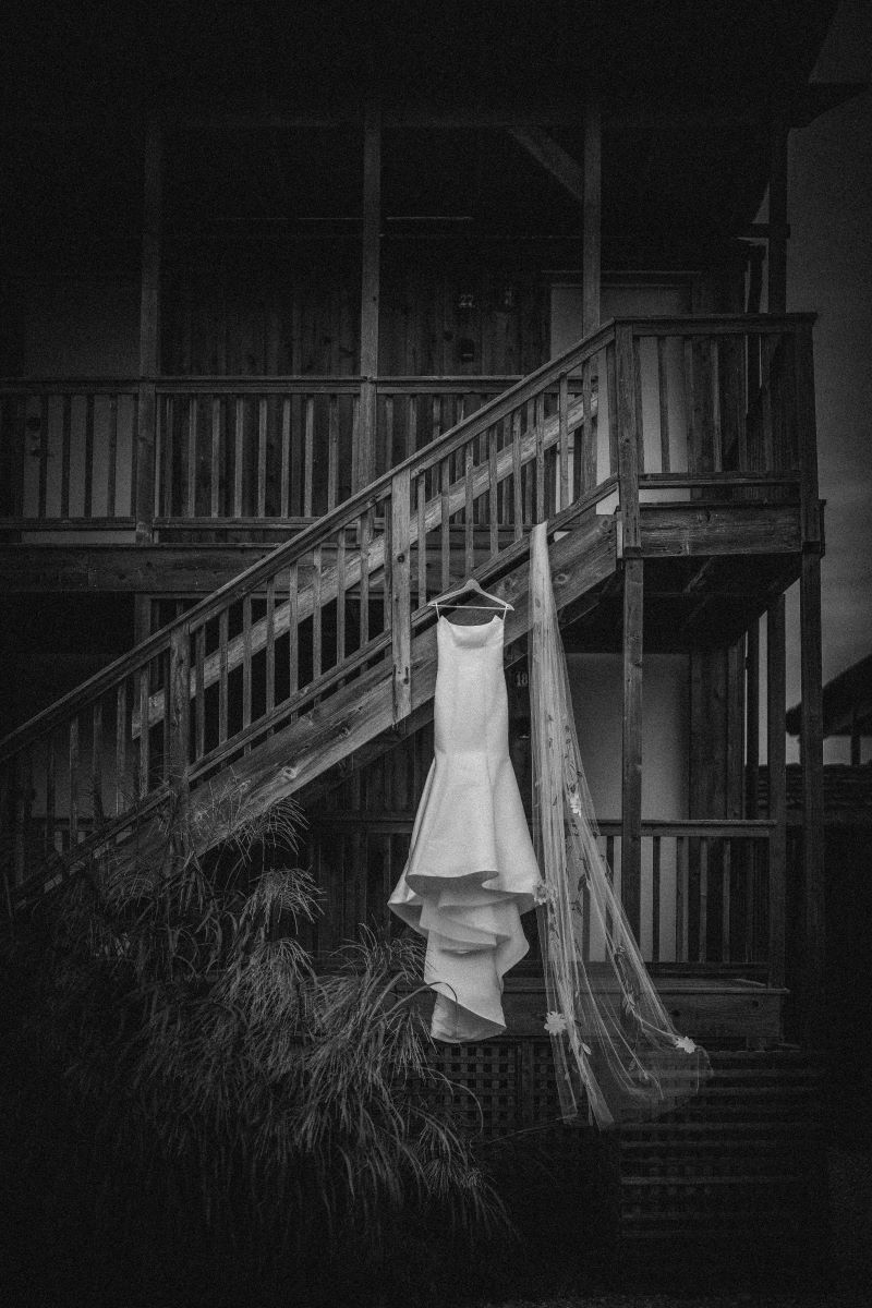 a wedding dress and veil are hanging off of some staris that lead to a house