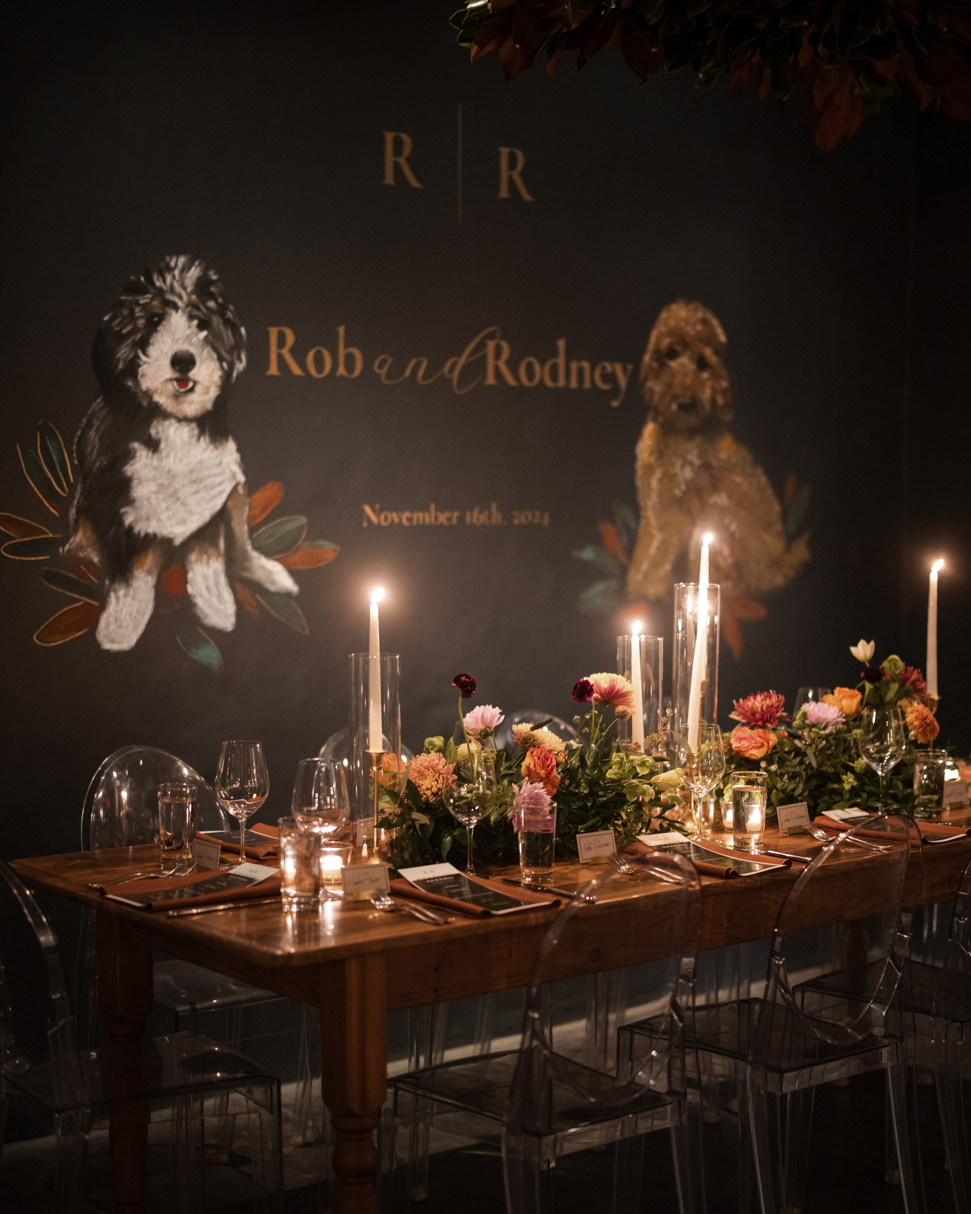 Elegant dining table setting with candles and flowers, set against a backdrop featuring illustrated dogs and the text "Rob and Rodney, November 16th, 2024." A subtle nod to The Little Owl Townhouse lends charm to this special occasion.