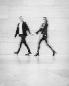 A couple in motion they are blurred, walking together and holding hands thorugh a museum