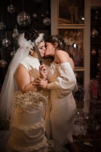 two women kissing in front of their wedding cake