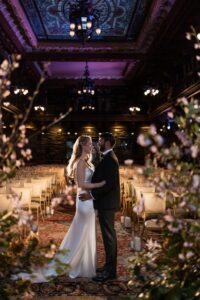 a couple hugging each other at their ceremony space inside the new york city yacht club the woman is wearing a white wedding dress the man is wearing a black tuxedo