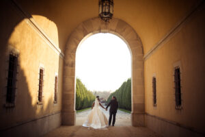 A newlywed couple standing under an archway in a castle