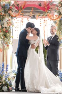 A bride and groom share a kiss under a decorated floral arch at their Water Works Philadelphia wedding