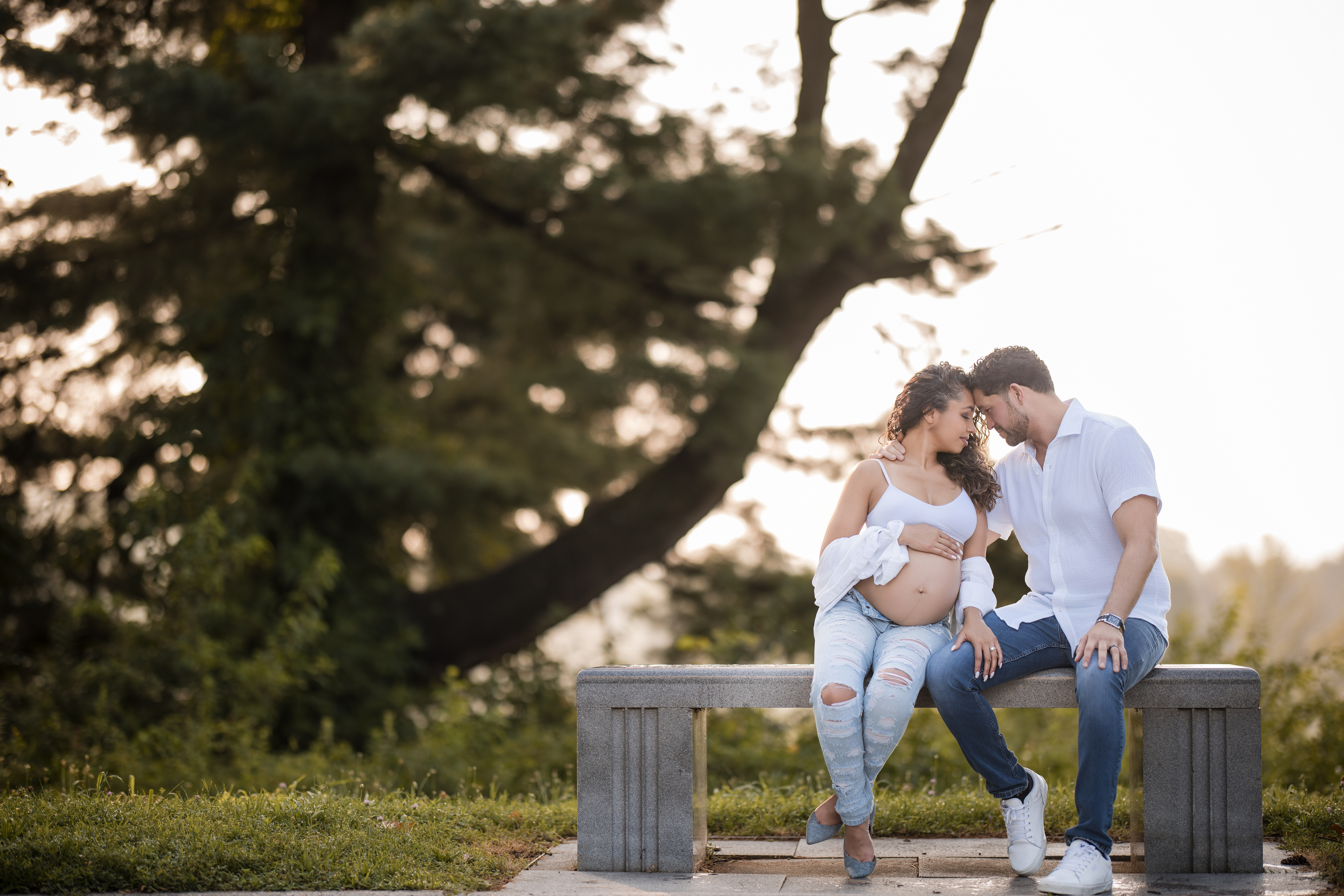 A couple cuddle on a bench during a maternity session at valley forge park