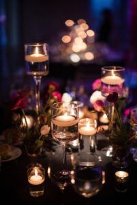A dimly lit table at an Angel Orensanz Wedding, decorated with floating candles in glass holders and small floral arrangements, creates a warm, elegant ambiance.