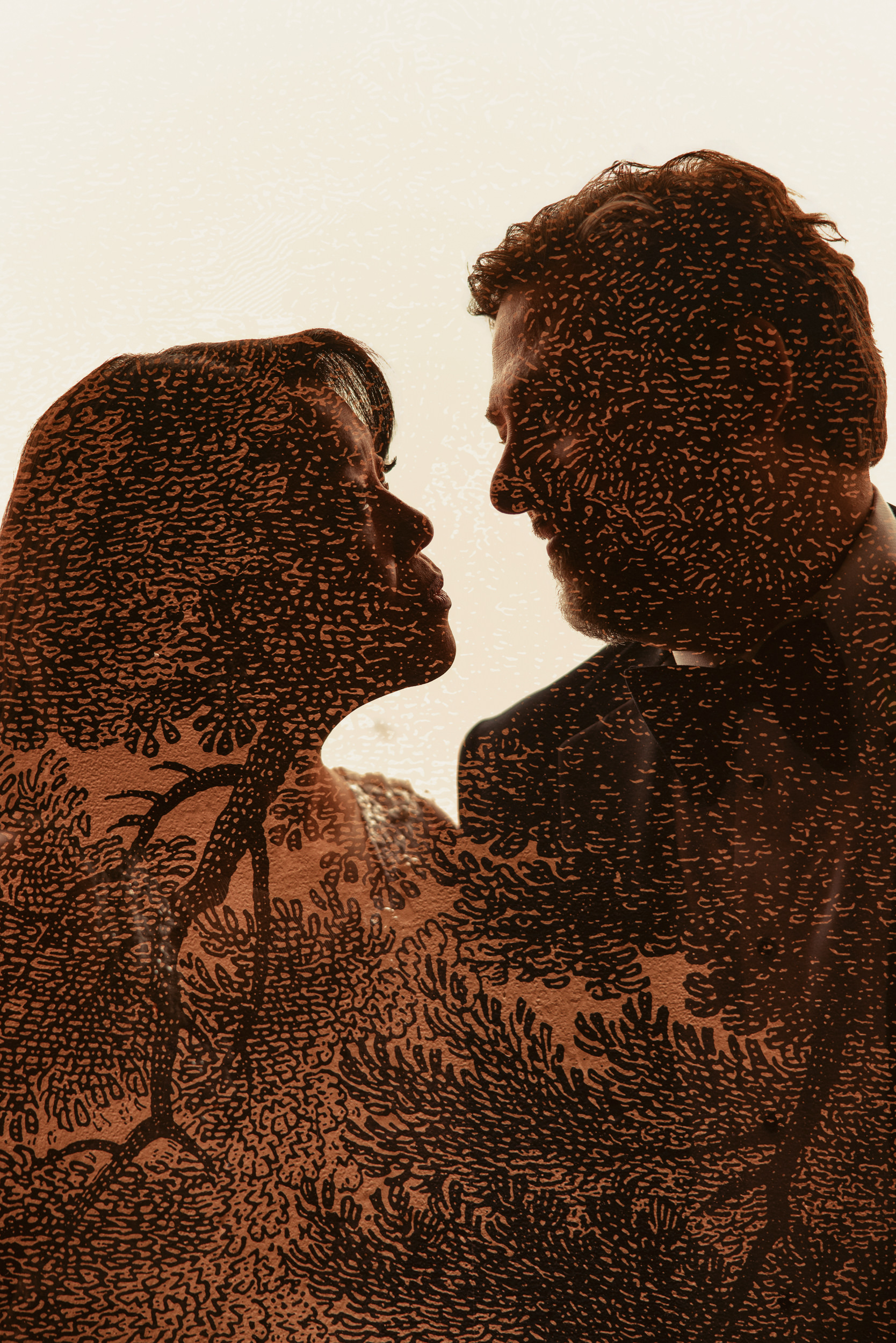 A double exposure image of a couple facing each other, overlaid with a pattern of tree branches and leaves, captures the romantic atmosphere of a Liberty Warehouse wedding.