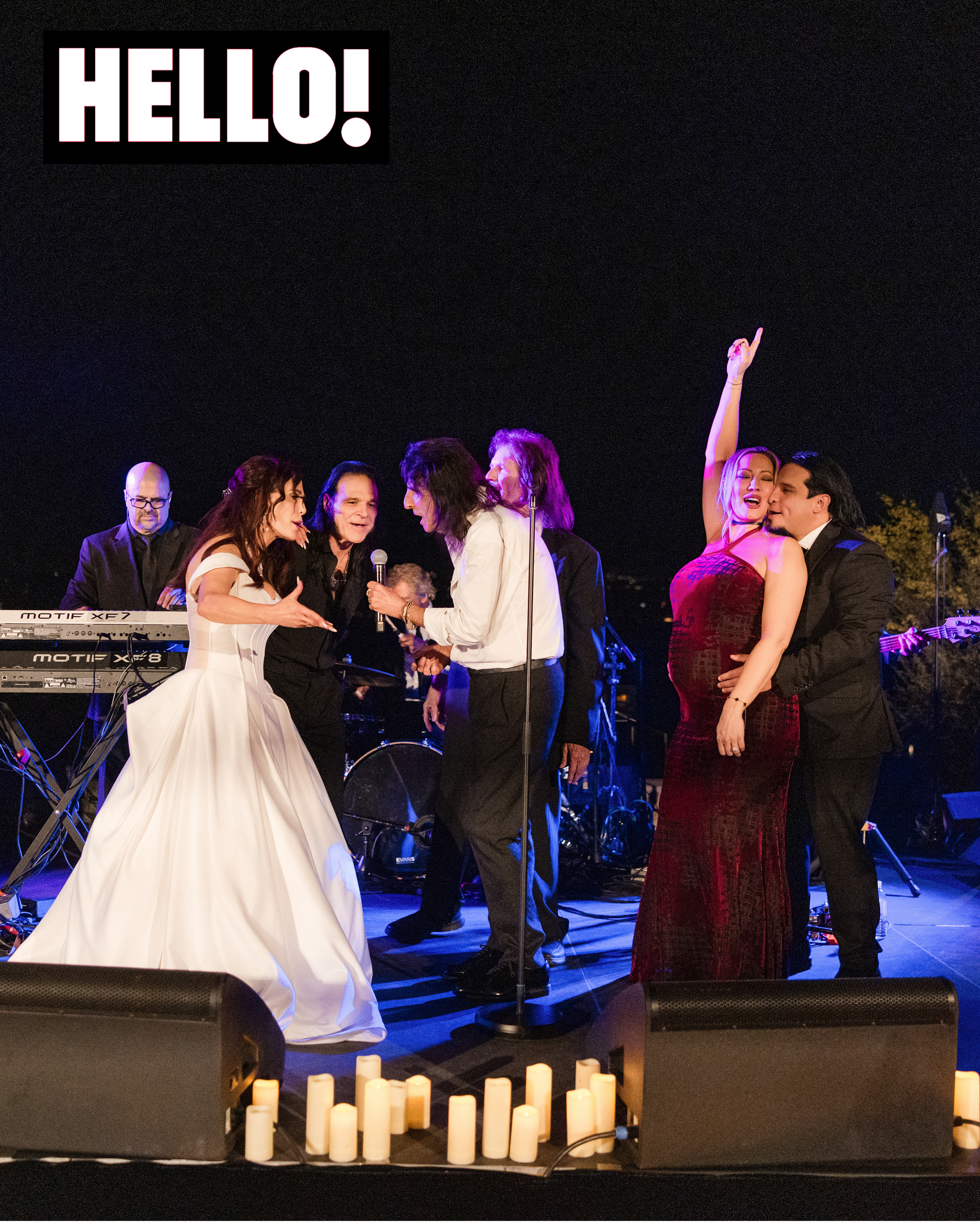 Alice Cooper and Sheryl Cooper stand on stage with musicians and guests at night, surrounded by candles. Other performers include Nita Strauss.