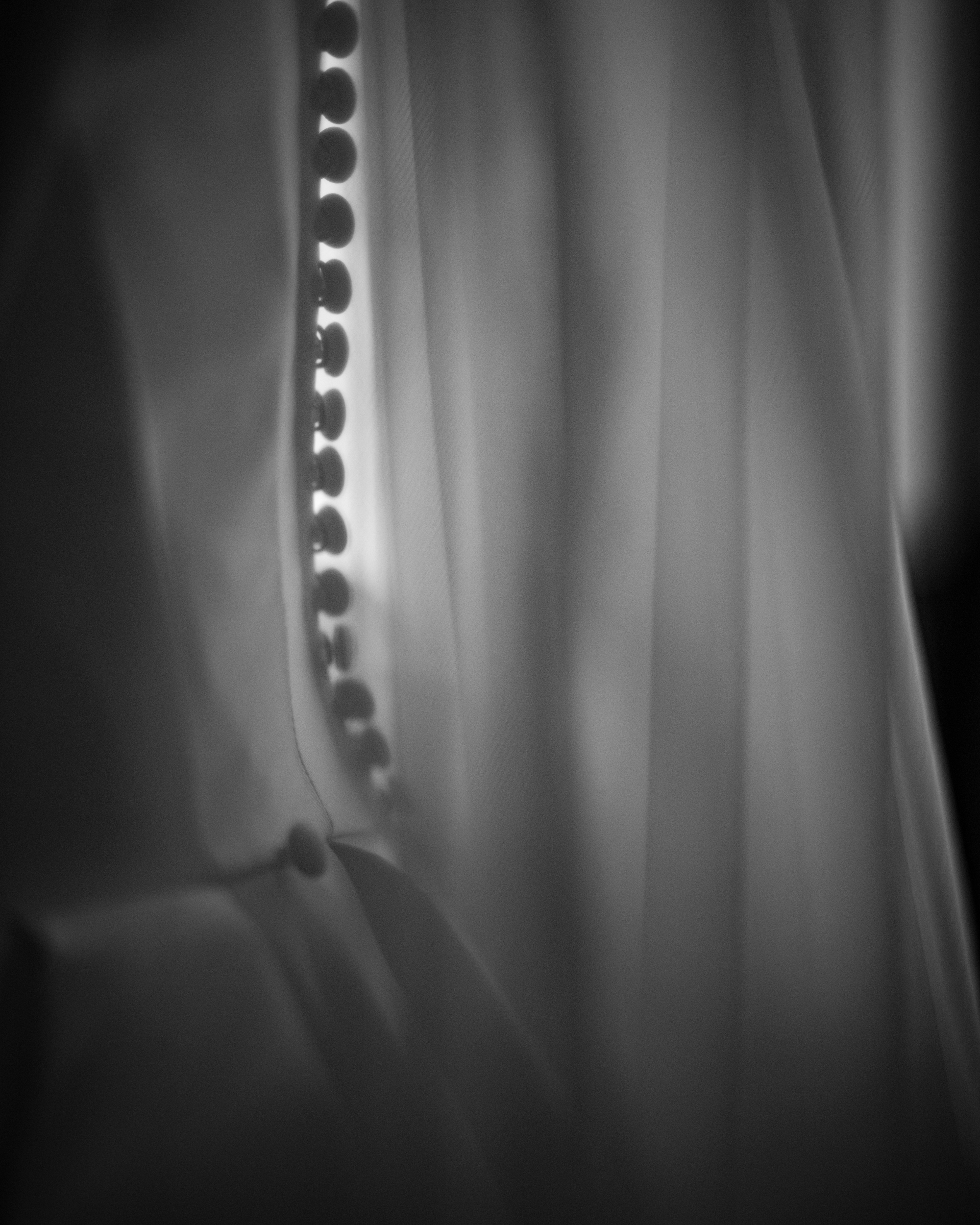 Close-up of fabric with a row of round buttons, likely part of a wedding dress or formal garment, shown in soft black and white lighting—capturing the elegance of a Downtown Club Philadelphia Wedding.