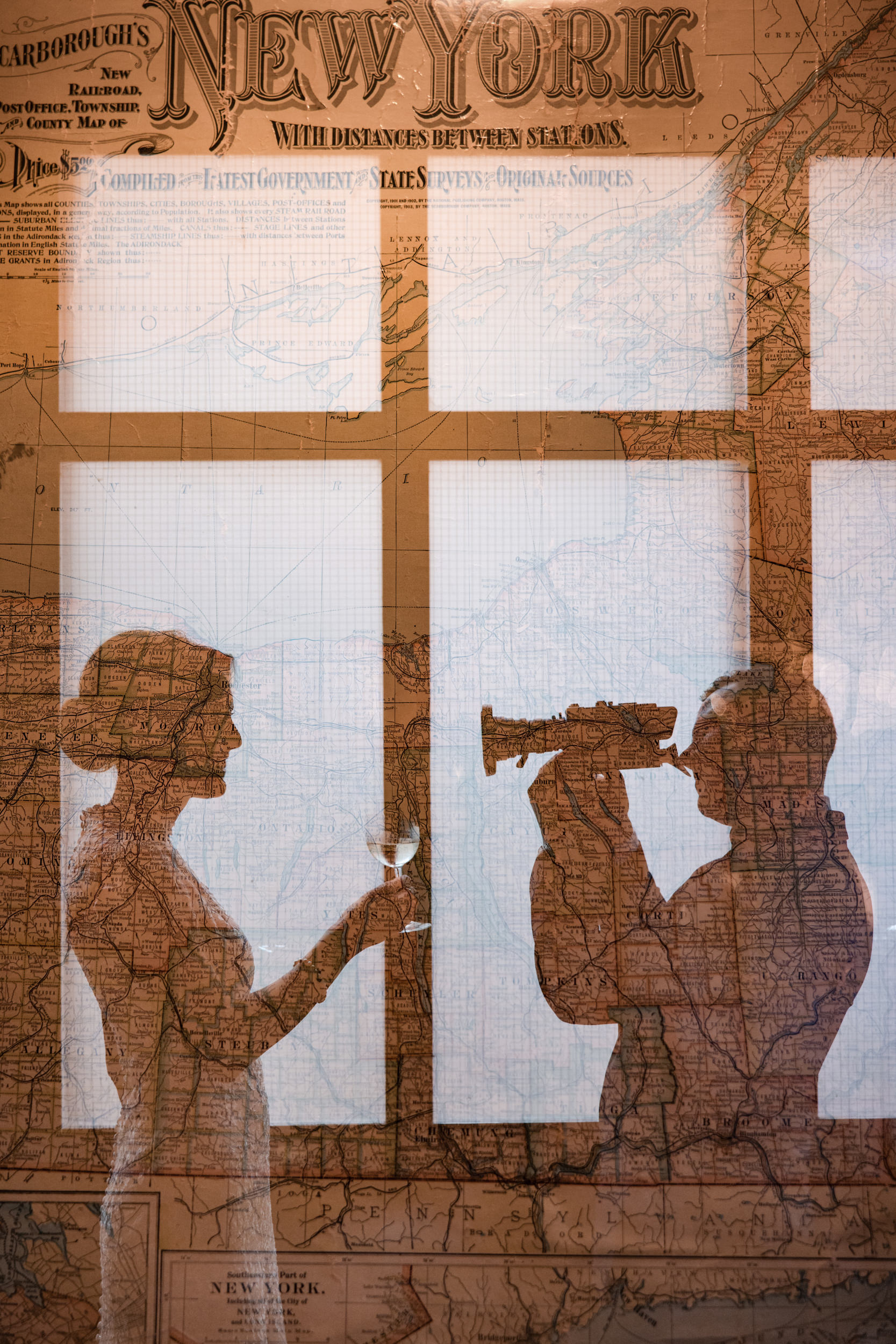 A silhouette of a woman holding a wine glass and a man looking through a telescope is overlaid on an old map of New York, evoking the timeless romance of a Houston Hall wedding.