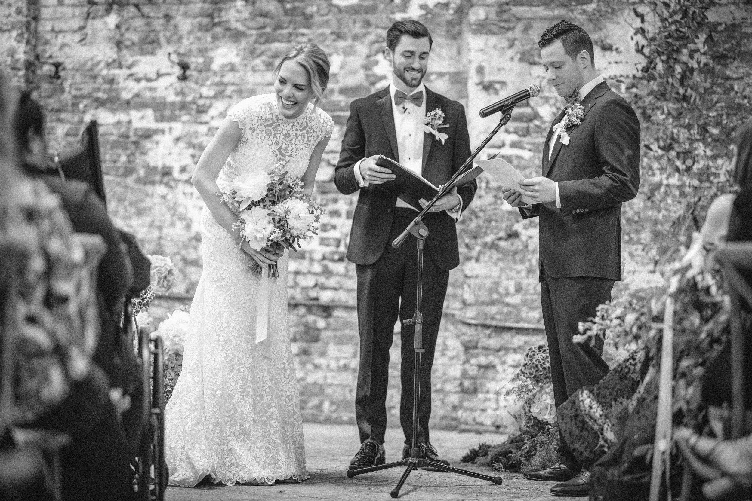 Bride laughing during a Houston Hall wedding ceremony with officiant and groom.