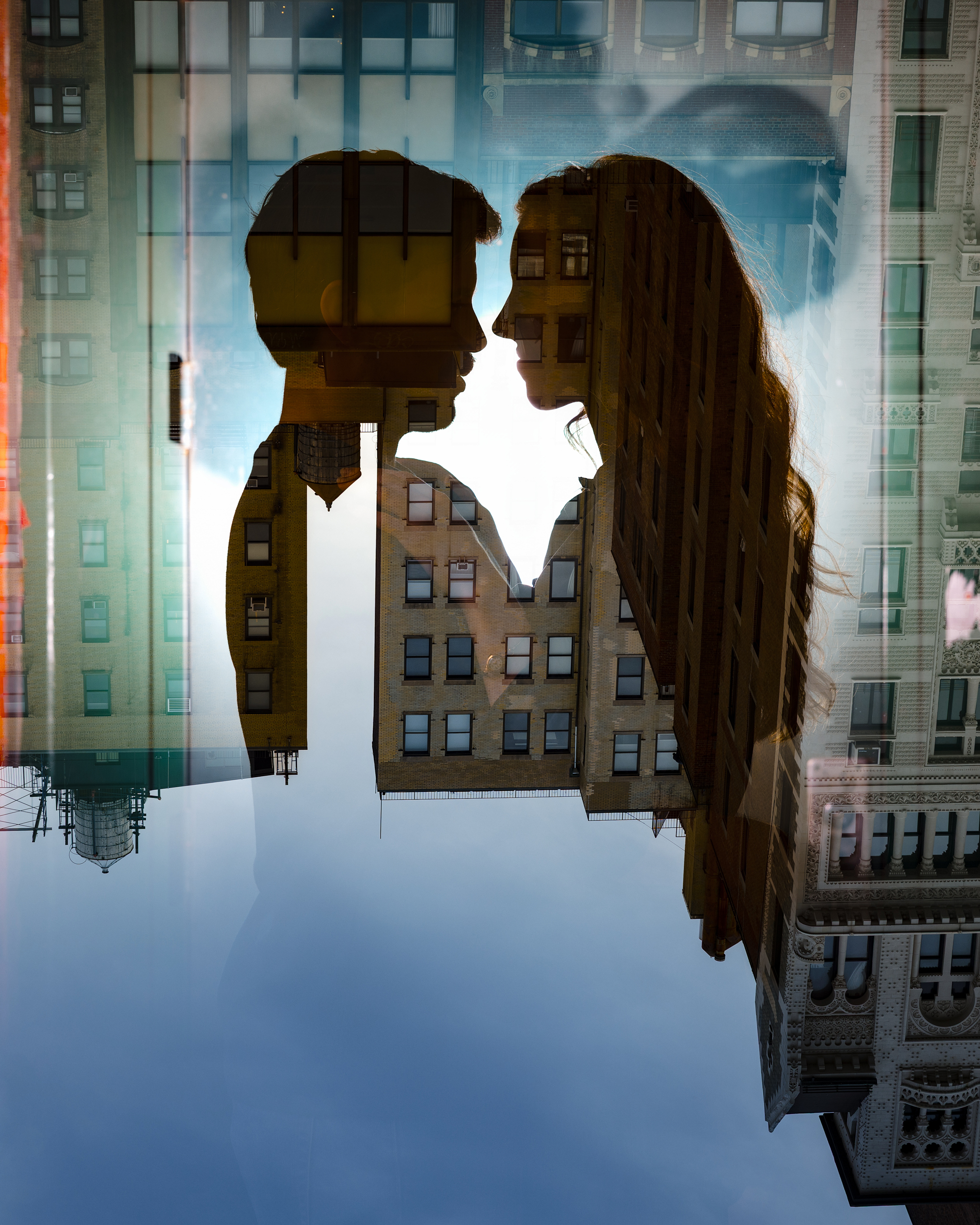 Double exposure image of two people facing each other, overlaid with tall city buildings against a blue sky—capturing the vibrant energy of an NYC photo walk.