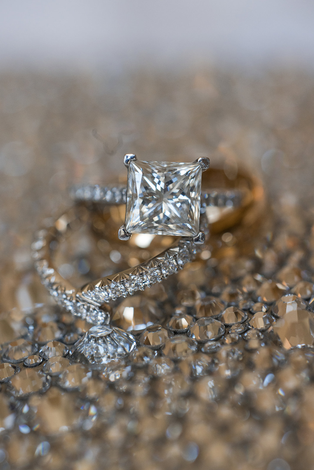 A close-up of a diamond engagement ring with a square-cut center stone and a twisted band encrusted with smaller diamonds, sparkling like the perfect accessory for a magical Guastavino's wedding.